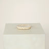 Marble-patterned dish on a light gray pedestal against a beige background