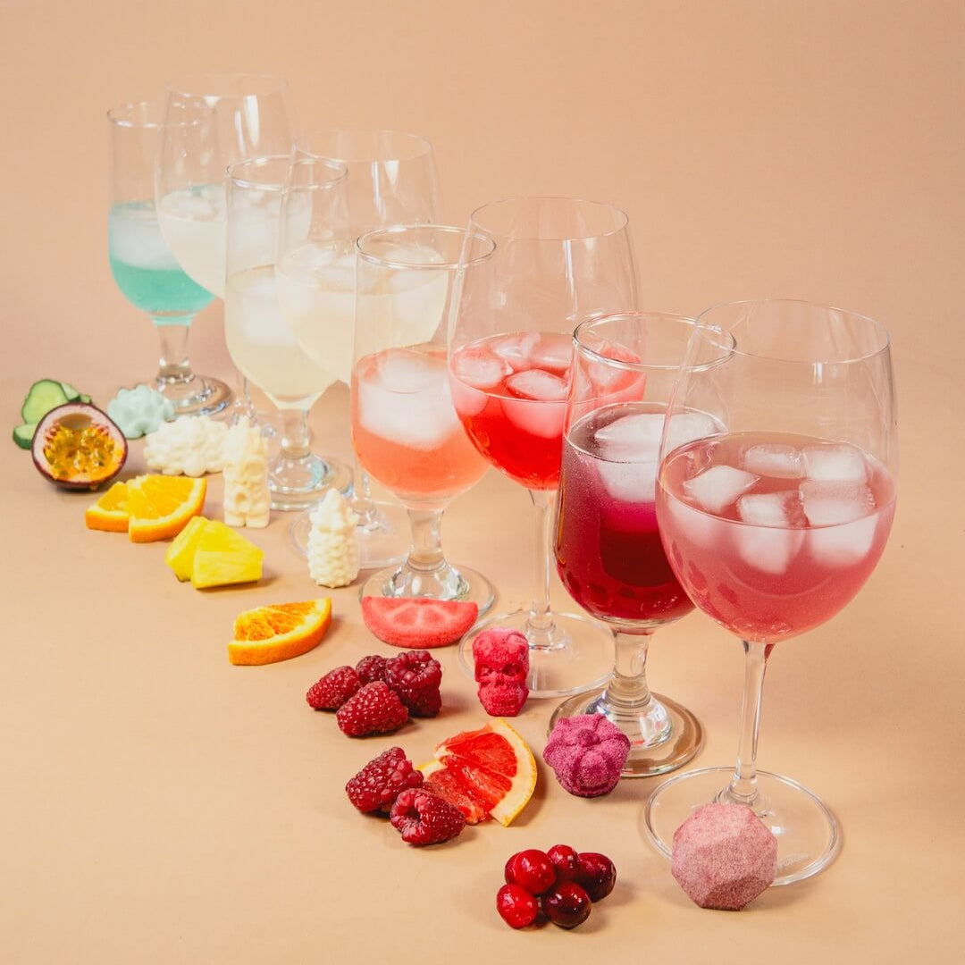 Poseidn Cocktail Variety Pack with cocktail bombs Assorted colorful cocktails with ice and fruits on a beige background
