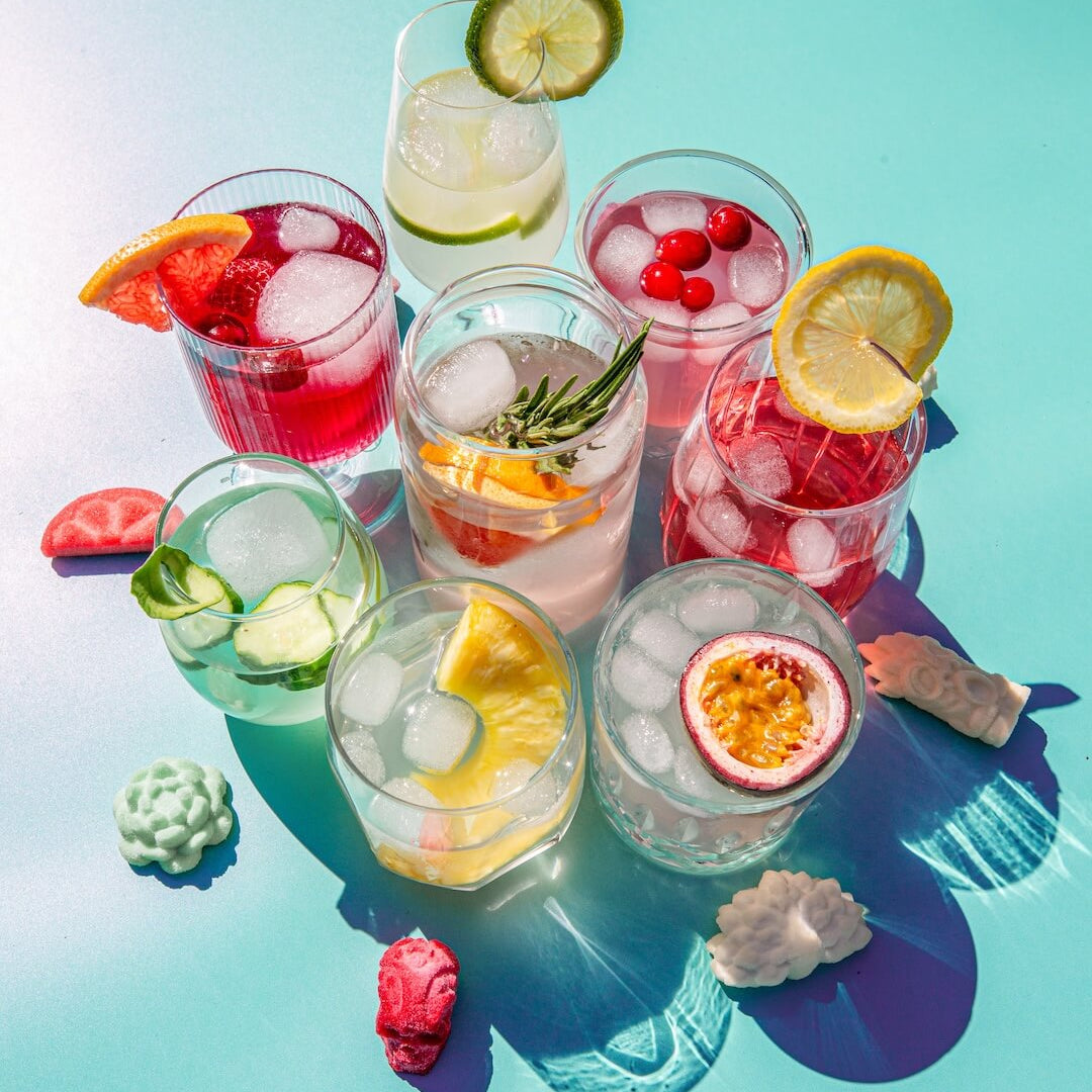 Assorted colorful cocktails with fruits and ice on a blue background from Poseidn Cocktail Variety Pack with cocktail bombs 