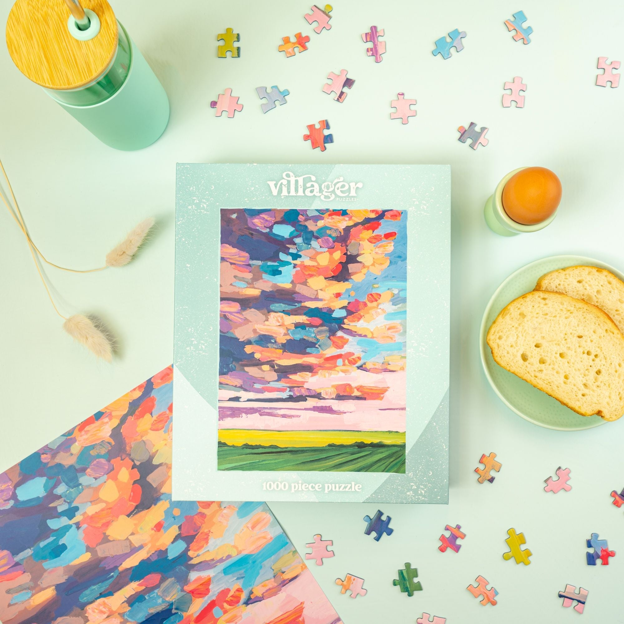 Villager puzzle box with colorful puzzle pieces and a drink on a light surface Prairie Sky | 1000-Piece Puzzle for Adults