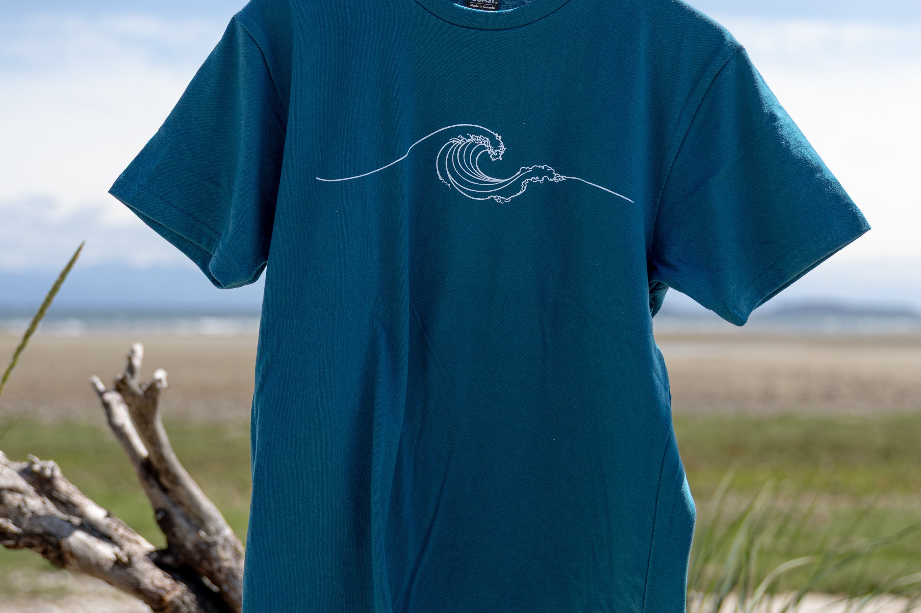 Blue t-shirt with a wave design on a wooden hanger against a natural background