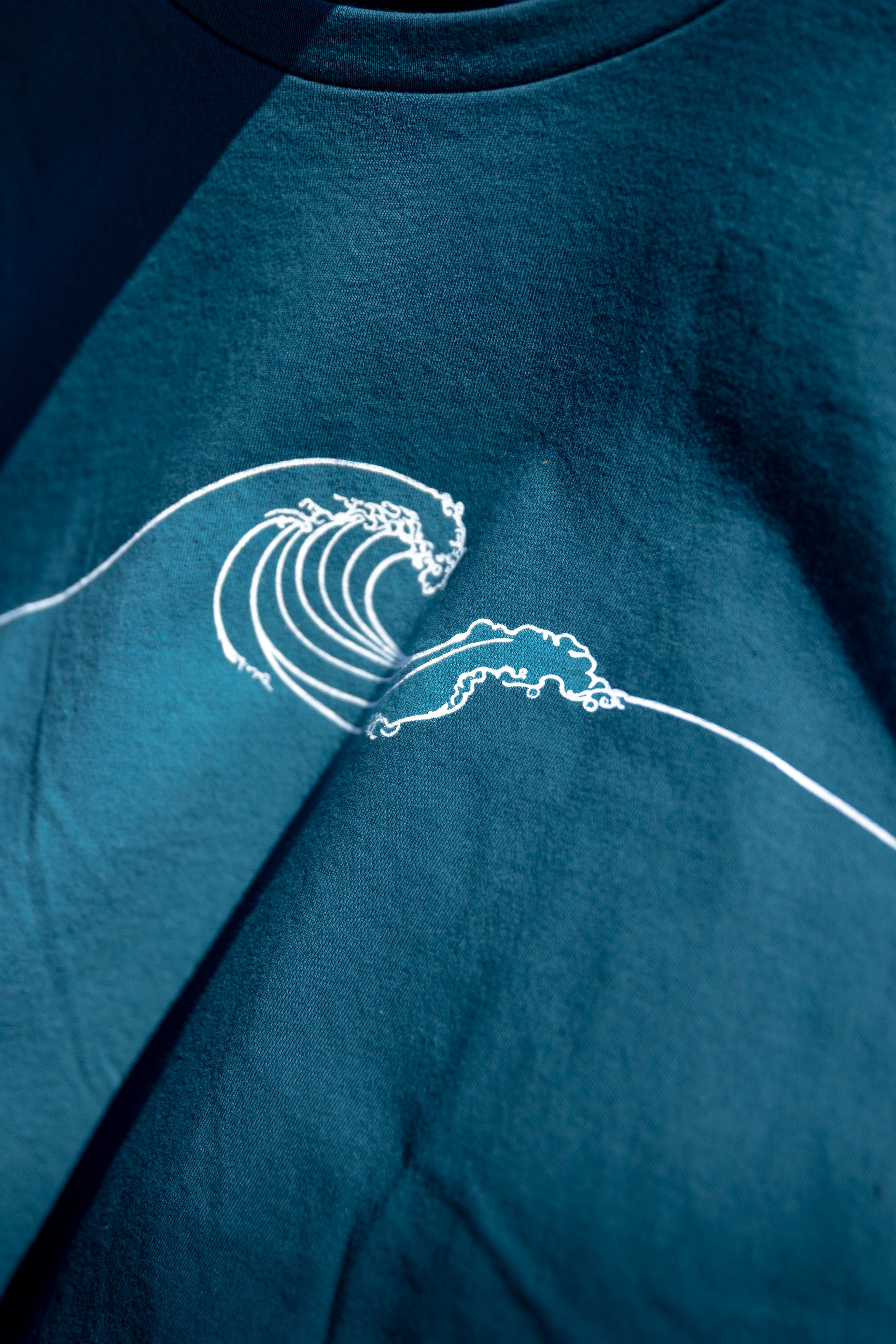 Blue t-shirt with a white wave design on a dark background