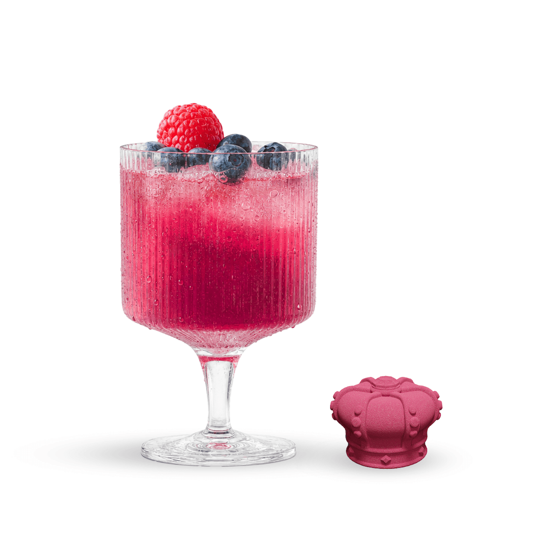 Pink cocktail in a glass with berries and a pink ice cube mold on a white background
