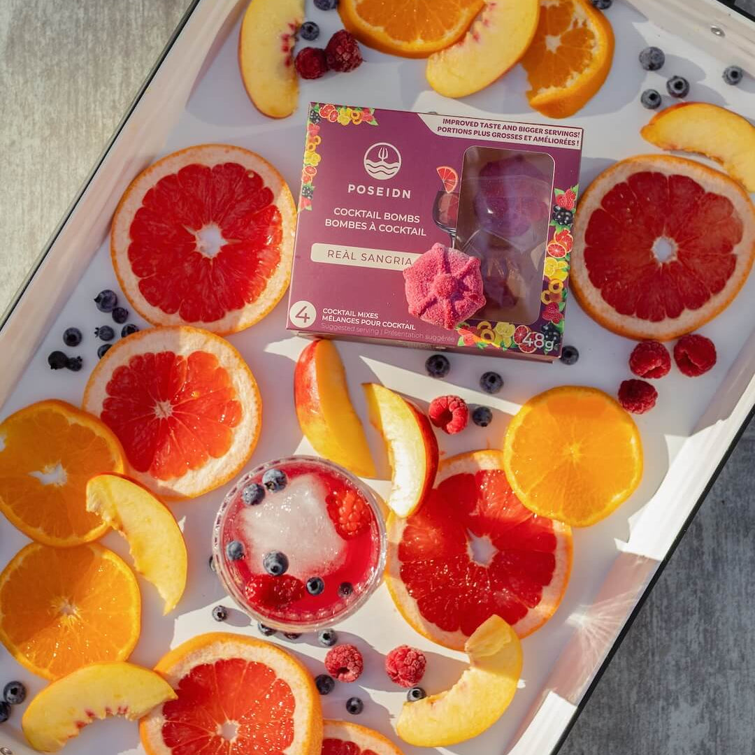 Fruit platter with oranges, grapefruits, and berries on a tray with a box of Positron Real Sangria.