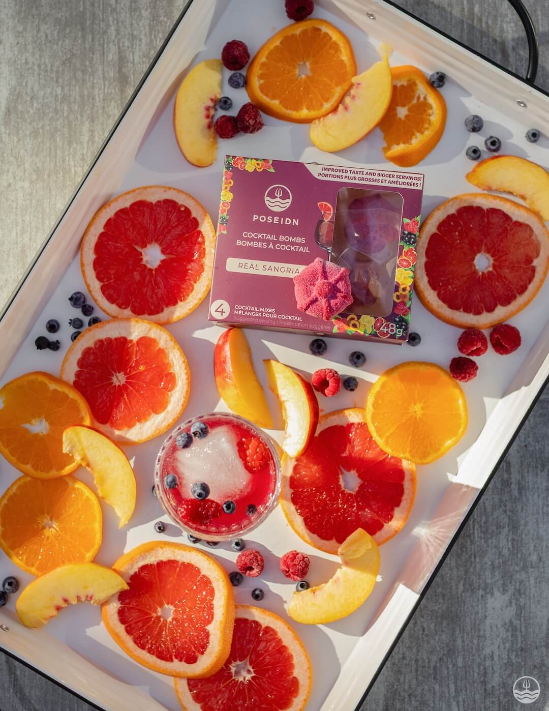 Fruit platter with oranges, grapefruits, and berries on a tray with a box of Positron Real Sangria.