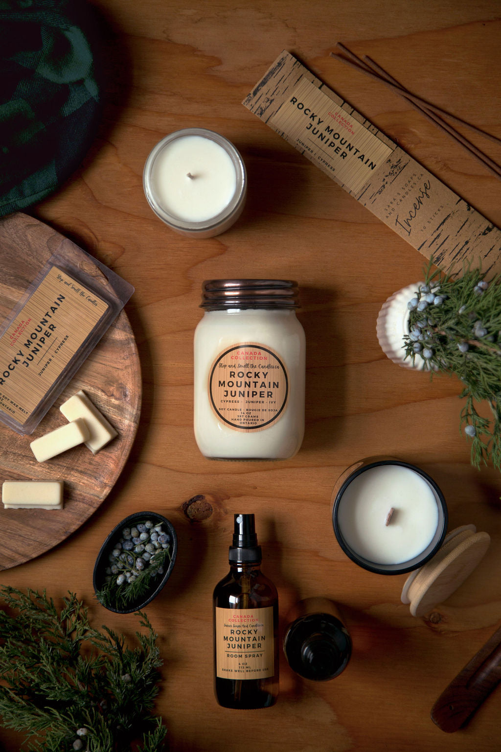 Candle and product set on a wooden surface with 'Rocky Mountain Juniper' branding.