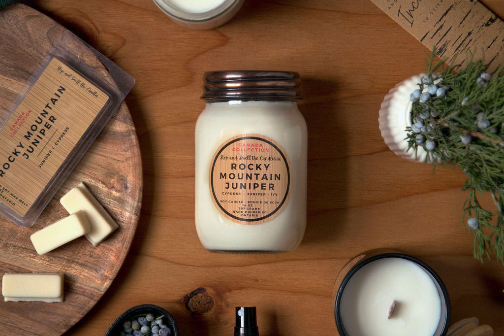 Candle and product set on a wooden surface with 'Rocky Mountain Juniper' branding.