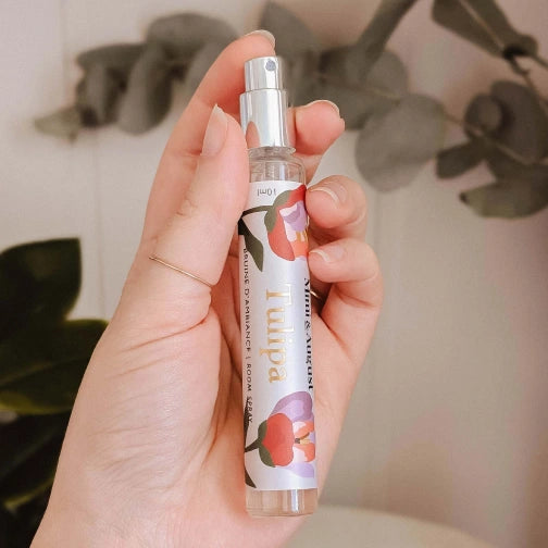 Hand holding a Room-spray-Tulipa with a floral design against a blurred background