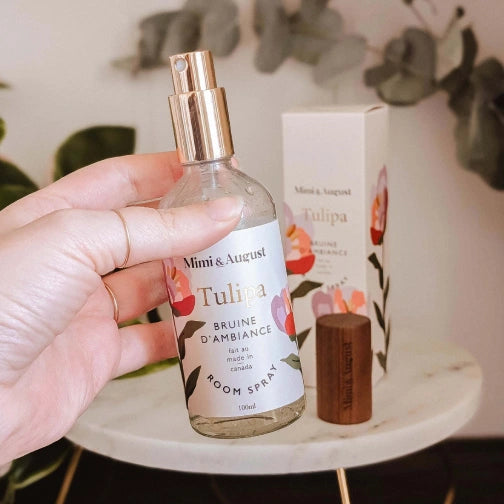 Hand holding a Mimi & August Tulipa room spray bottle with packaging in the background.