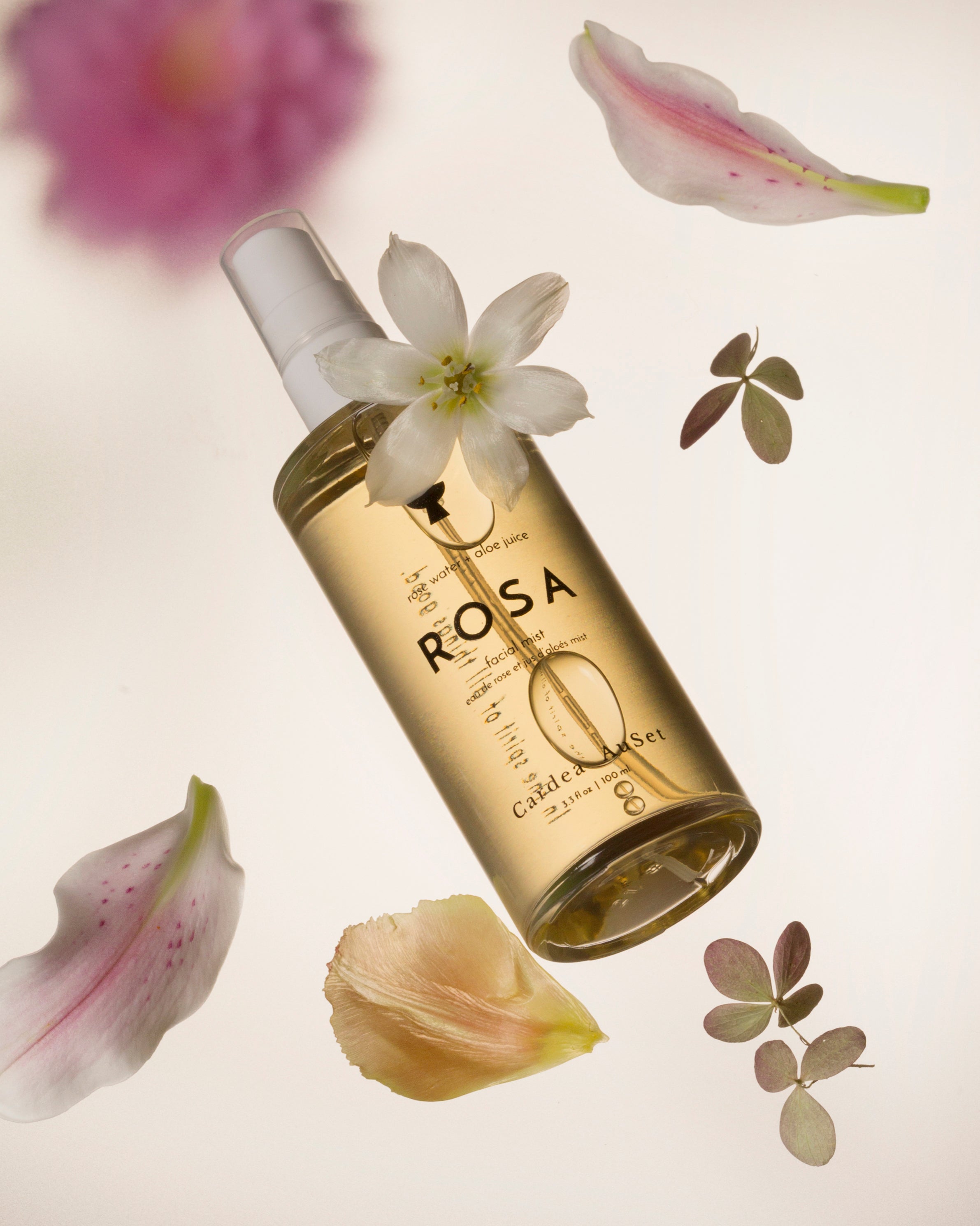 Gold bottle labeled 'ROSA' with flowers and leaves on a light background