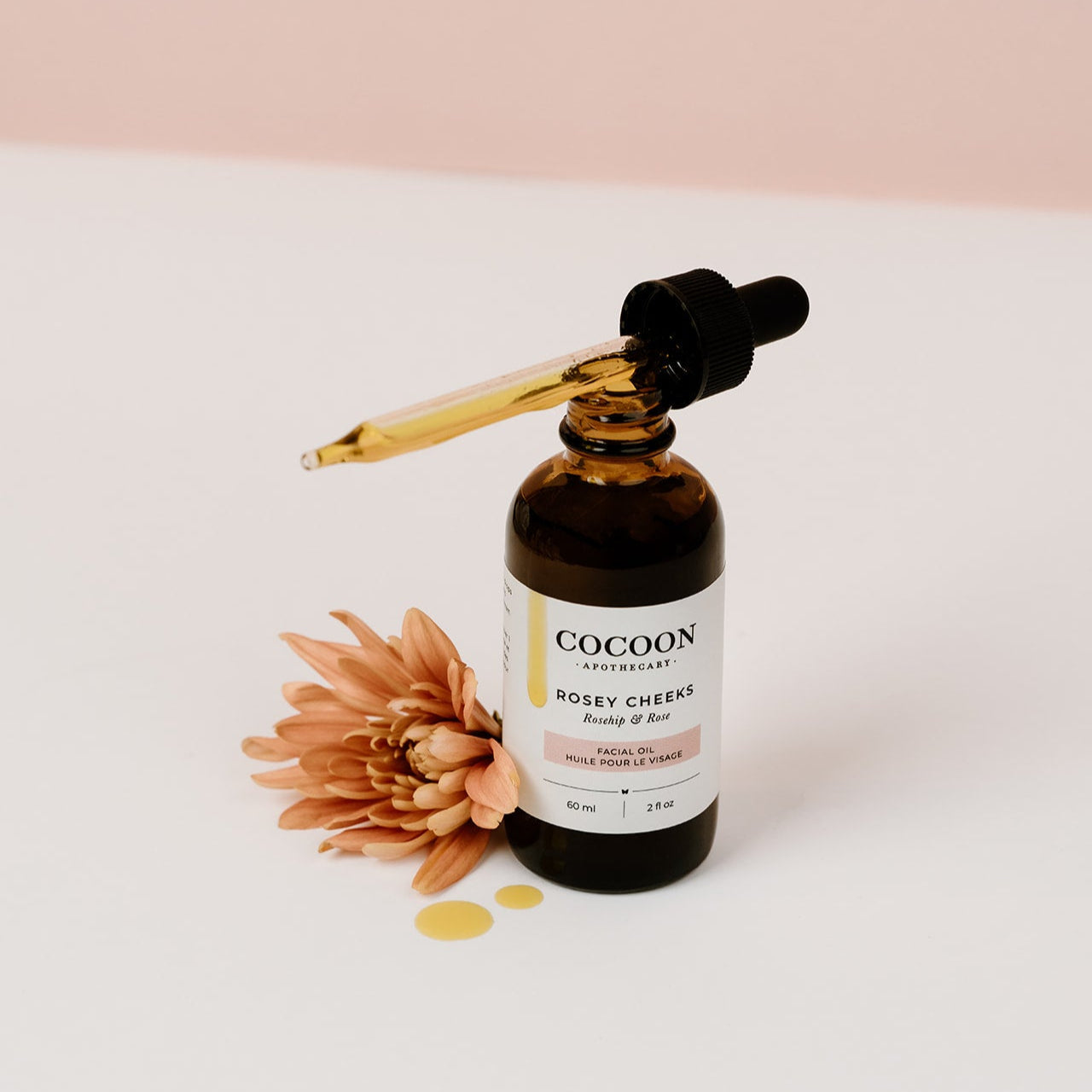 Cocoon skincare bottle with dropper and flower on a light background