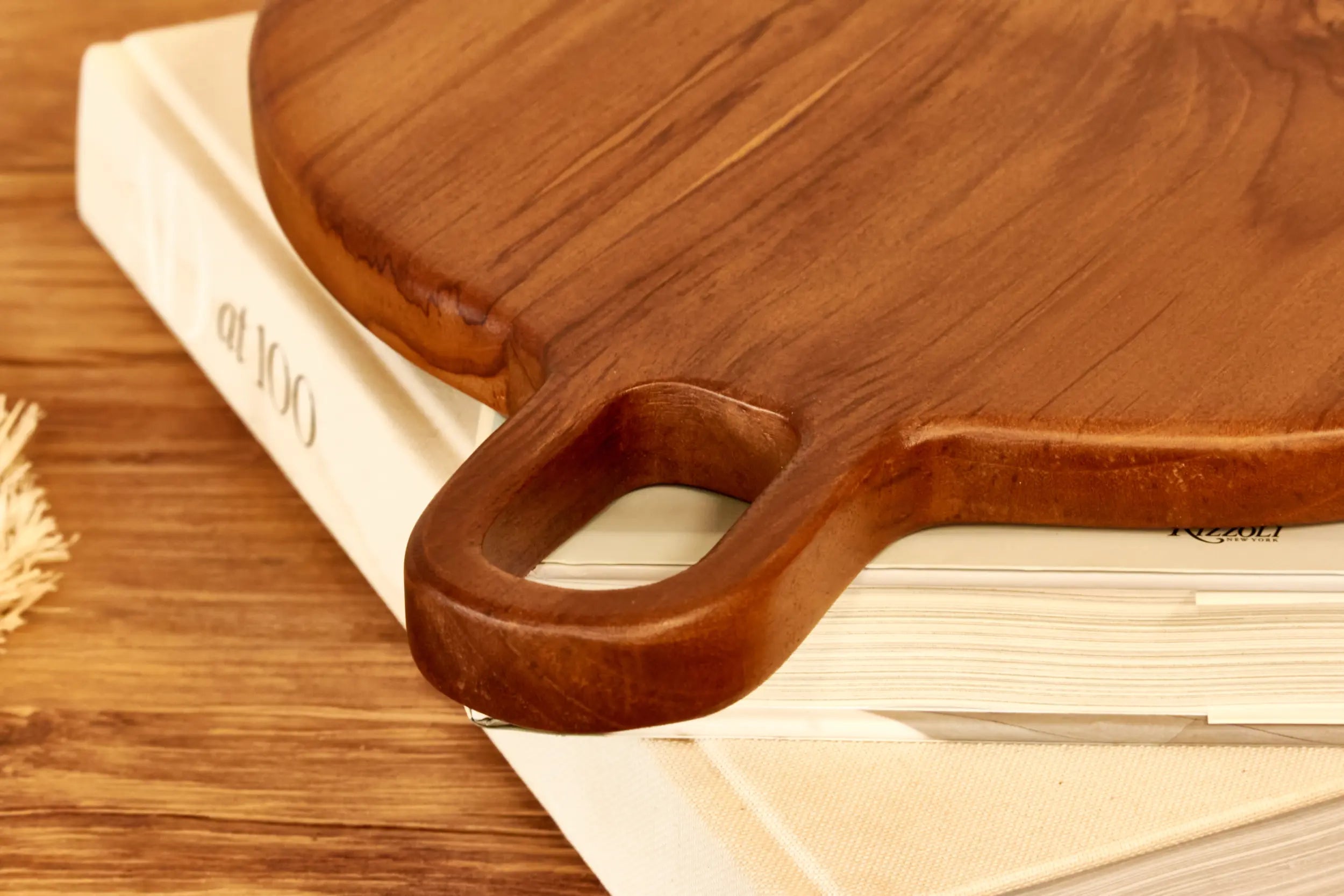 Wooden  teakcutting board with handle on a book