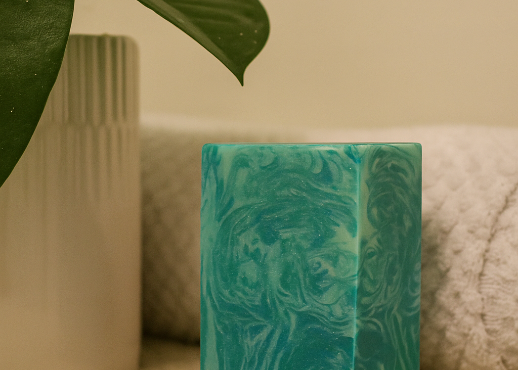 Green marbled candle on a textured surface with a plant leaf in the corner