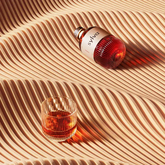 Sylva bottle and glass of amber liquid on a textured beige surface  The Sobr Market