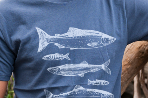 Man wearing a blue t-shirt with white fish illustrations outdoors.