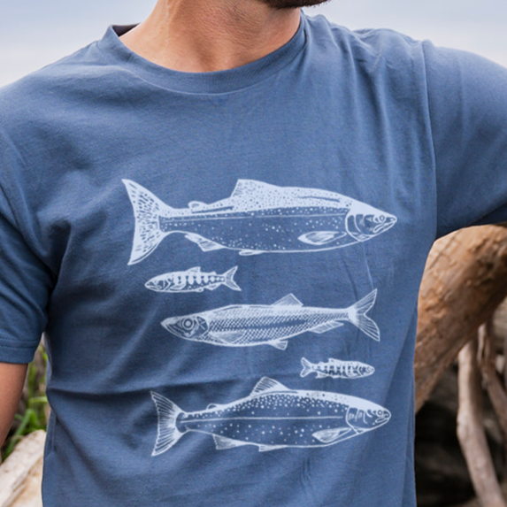 Man wearing a blue t-shirt with white fish illustrations outdoors.