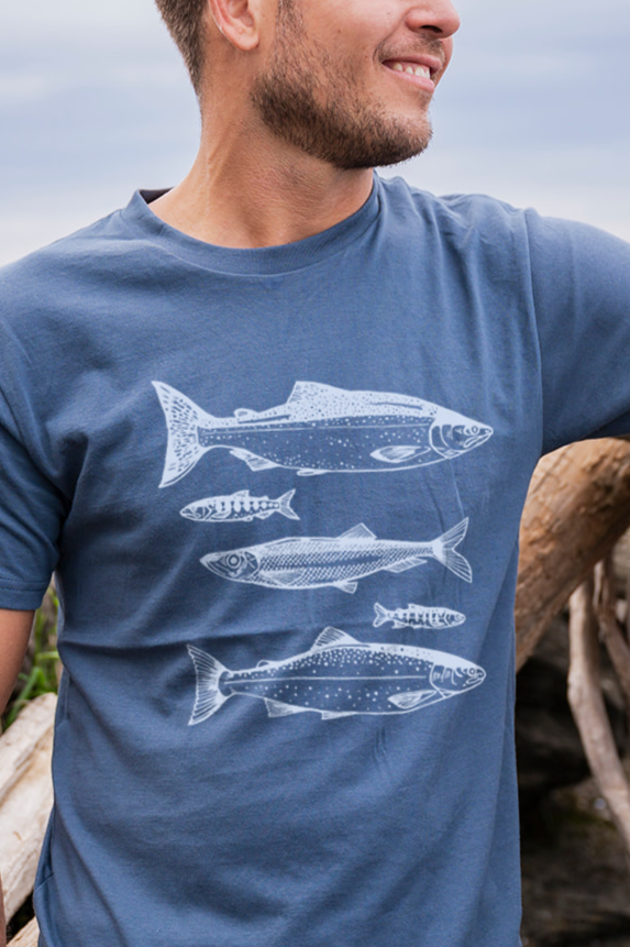 Man wearing a blue t-shirt with white fish illustrations outdoors.
