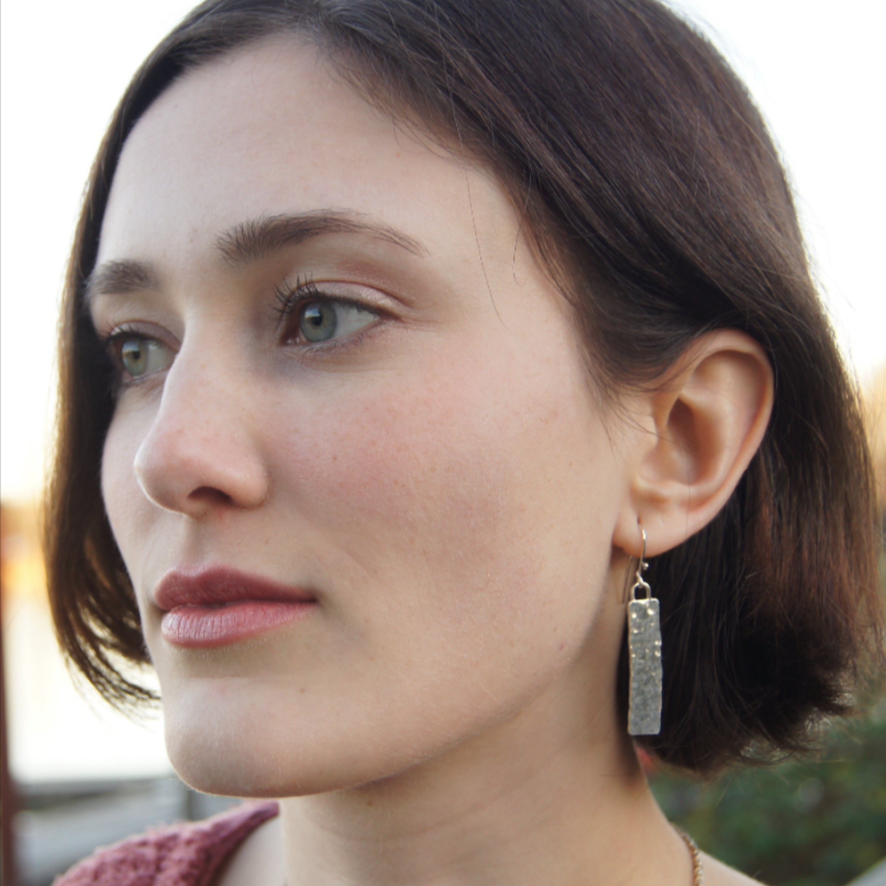 Close-up of a woman wearing Juliet925 Monolith earrings with hammered silver rectangles