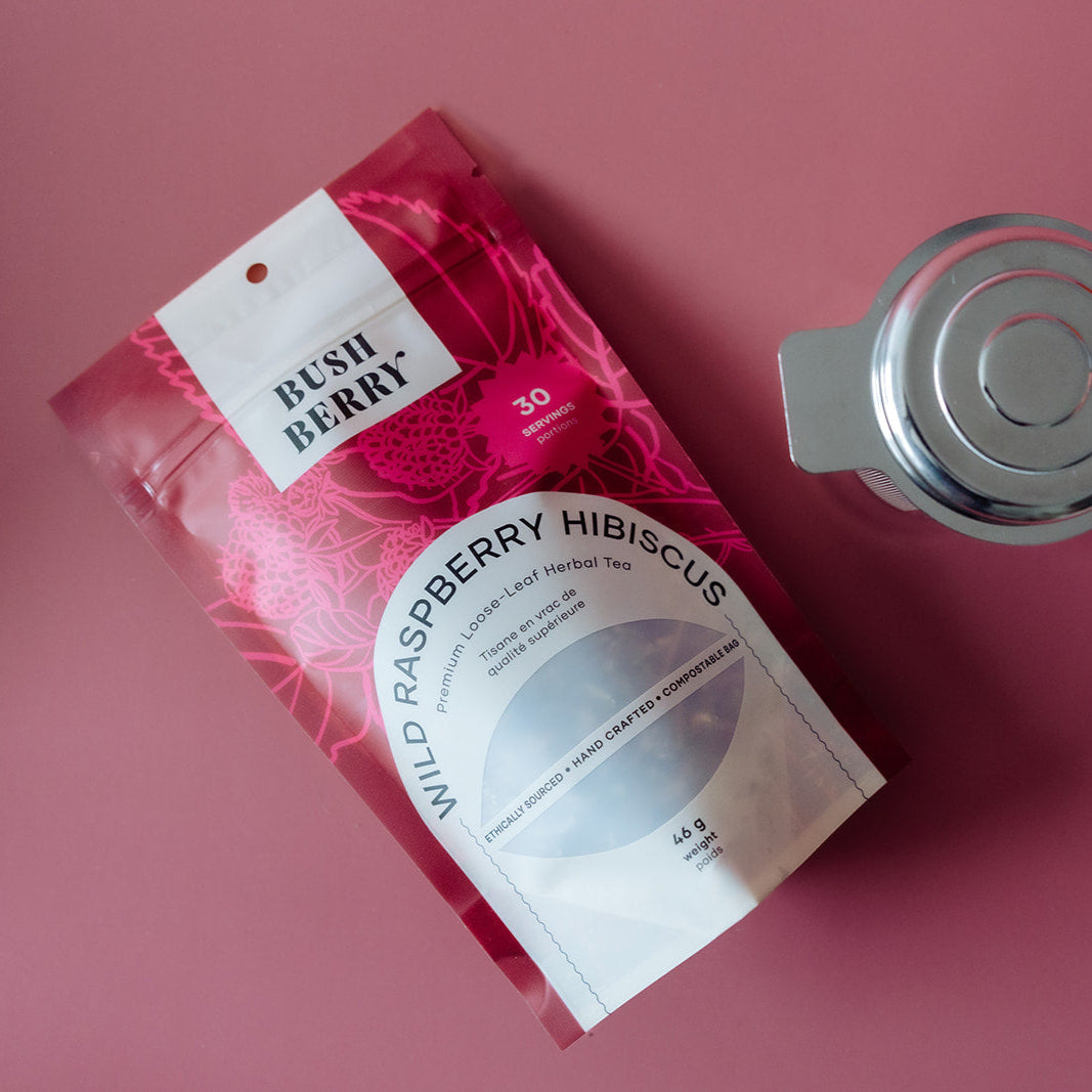 Packaging of Bush Berry Wild Raspberry Hibiscus tea on a pink background