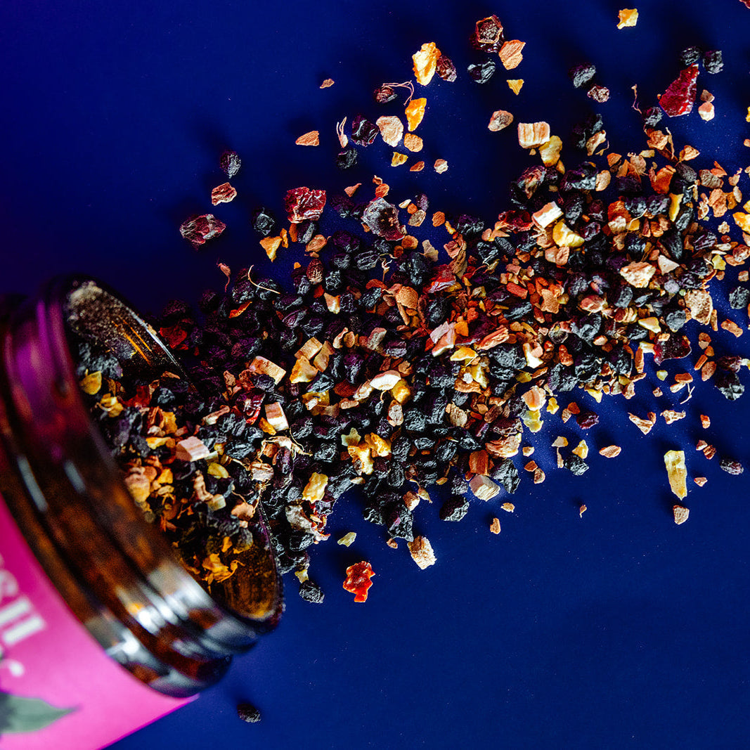Spices spilling out of a pink bottle onto a blue surface