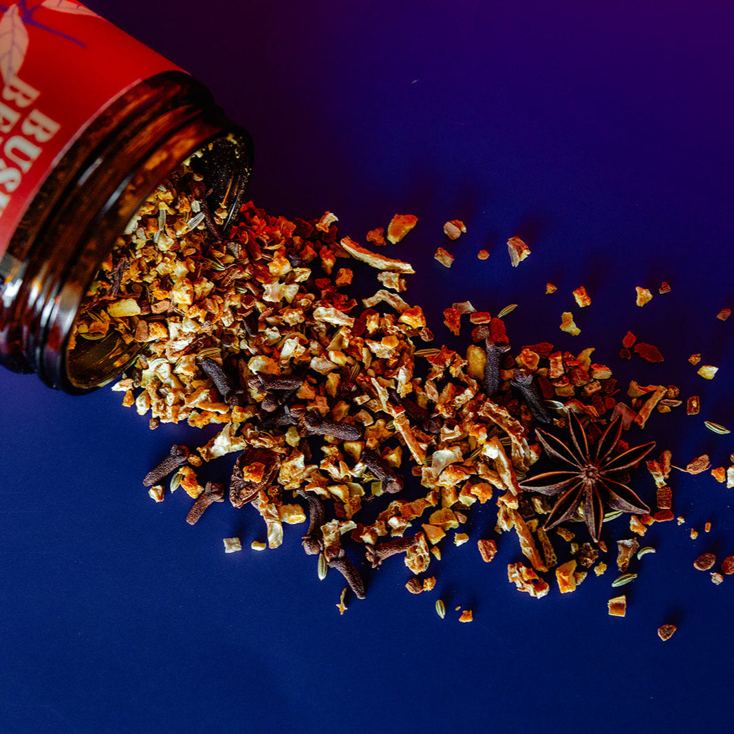 Spices spilling out of a jar with a red label on a blue background
