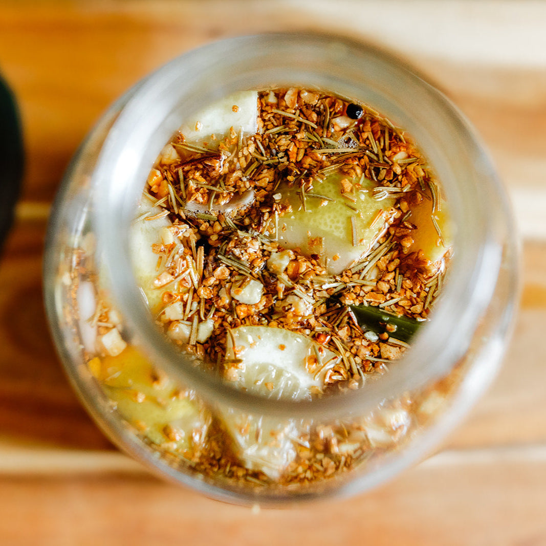 Close-up of a glass jar with a mixture of herbs and vegetables on a wooden surface