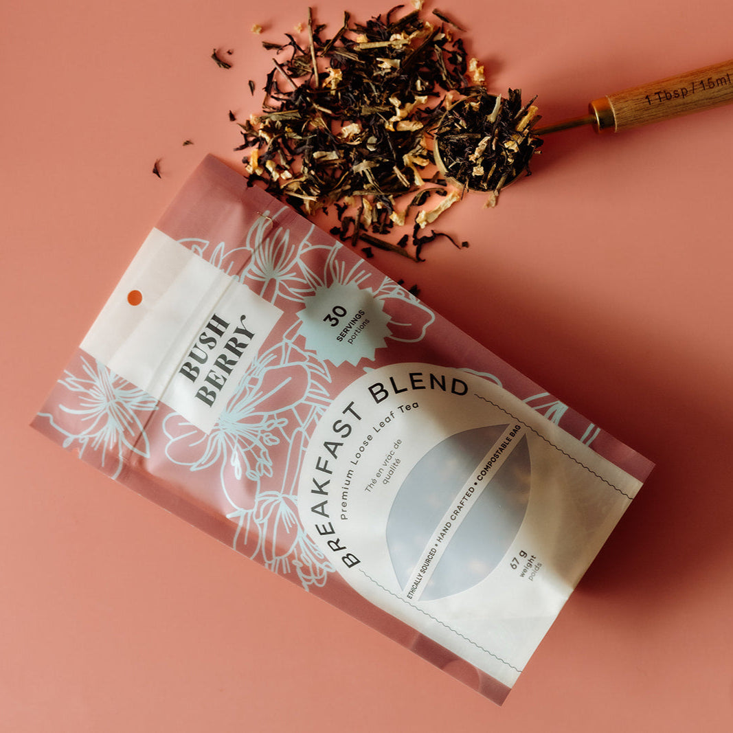 Tea package labeled 'Breakfast Blend' with dried tea leaves on a pink background