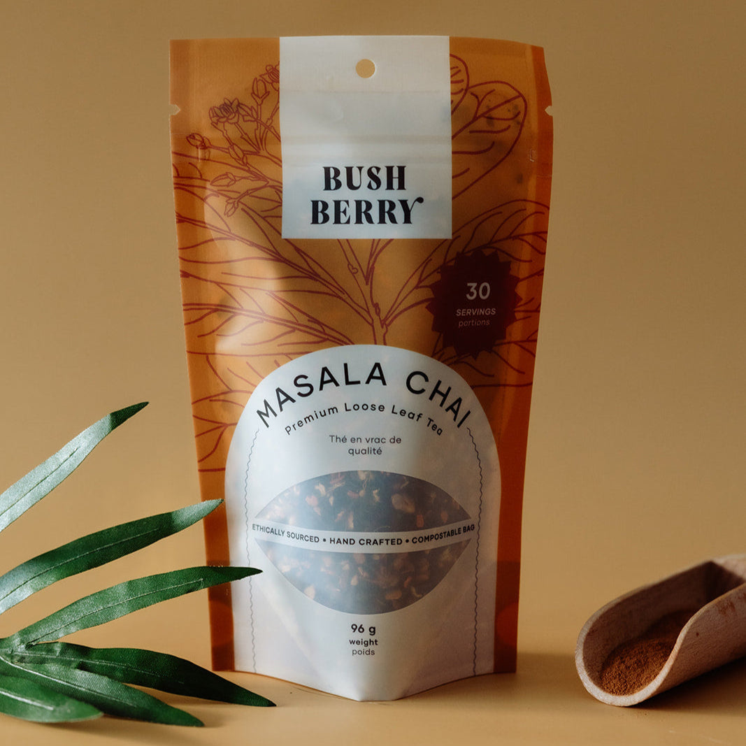 Bush Berry Organic Masala Chai Tea on a beige background with a leaf and scoop.