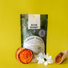 Bush Berry Throat Sooth tea package on a yellow background with dried orange slices and a wooden scoop.