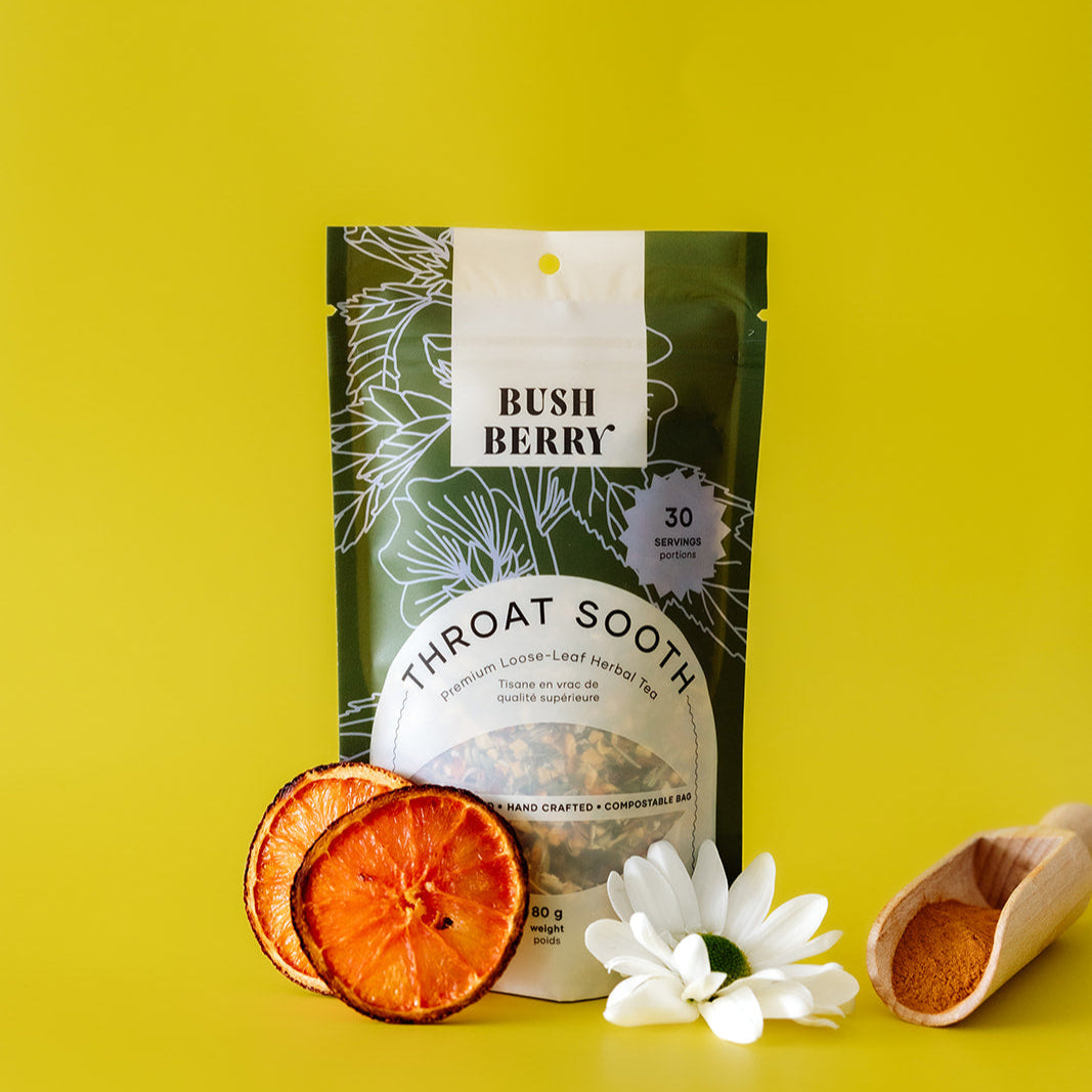 Bush Berry Throat Sooth tea package on a yellow background with dried orange slices and a wooden scoop.