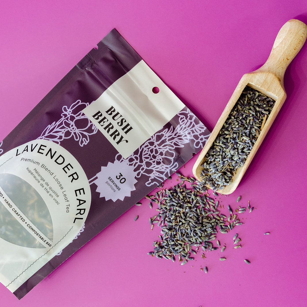 Lavender ear tea package with a wooden scoop of lavender buds on a pink background