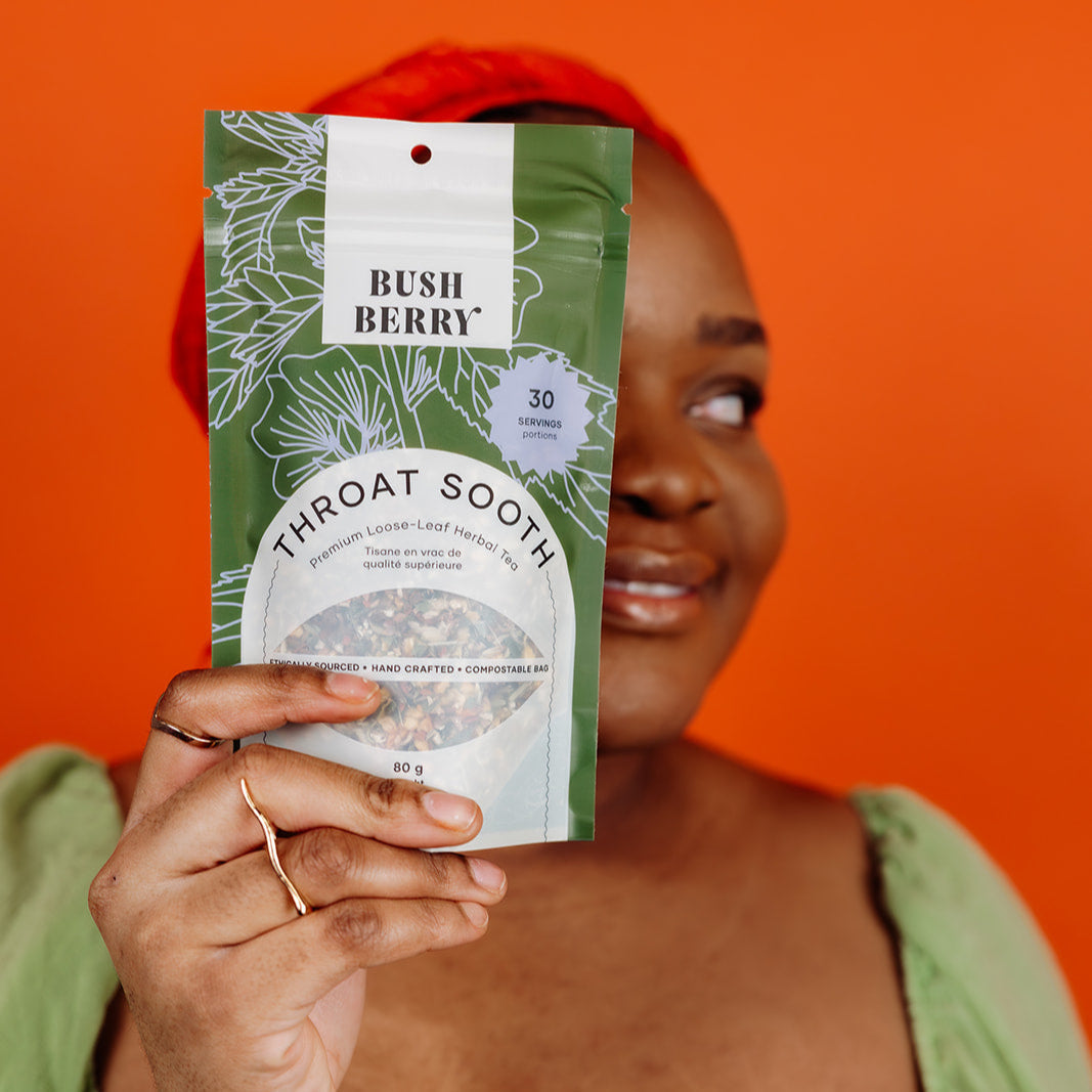 Person holding a 'Bush Berry Throat Sooth' package against an orange background