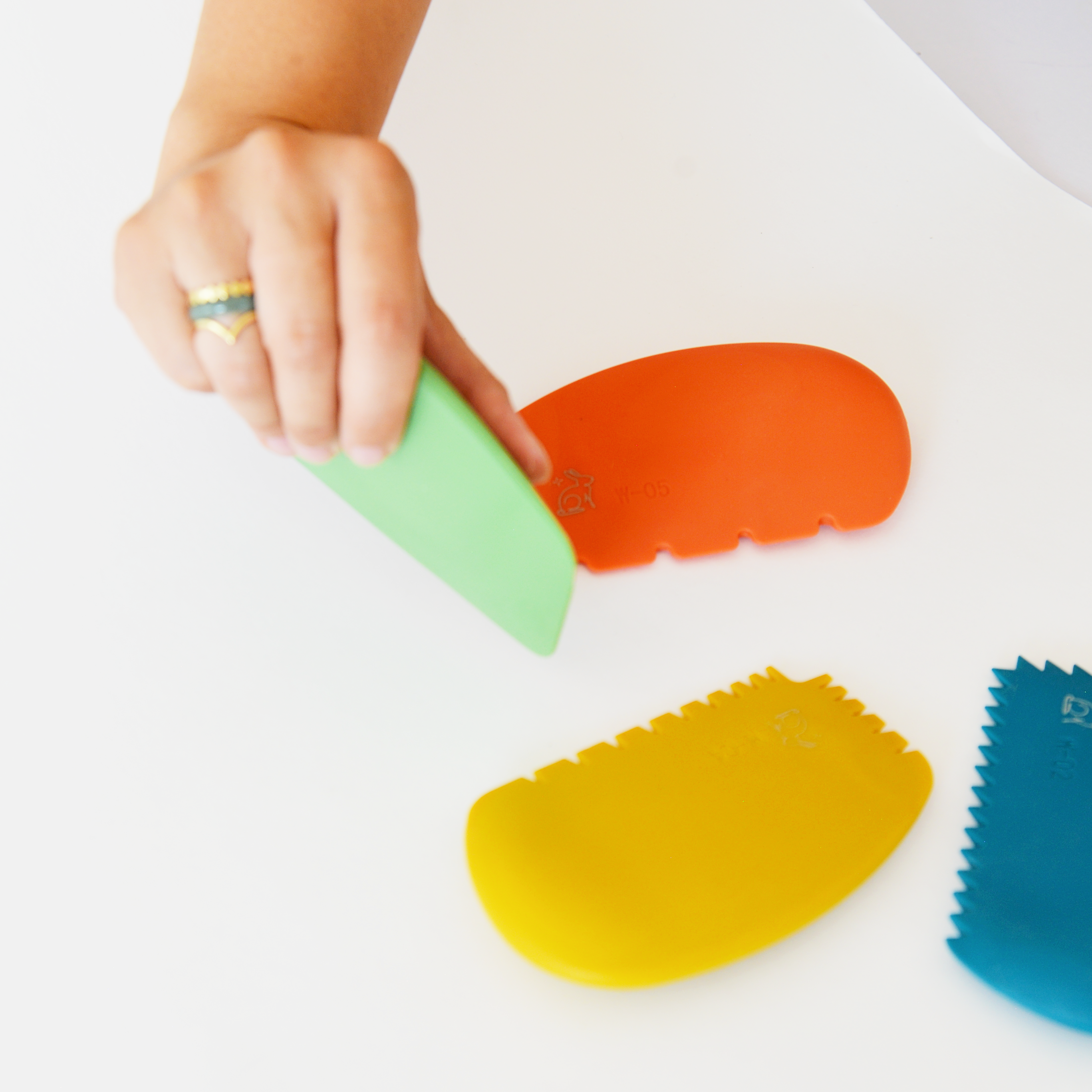 Colorful silicone paint wedges on a white surface with a hand interacting with one of them.