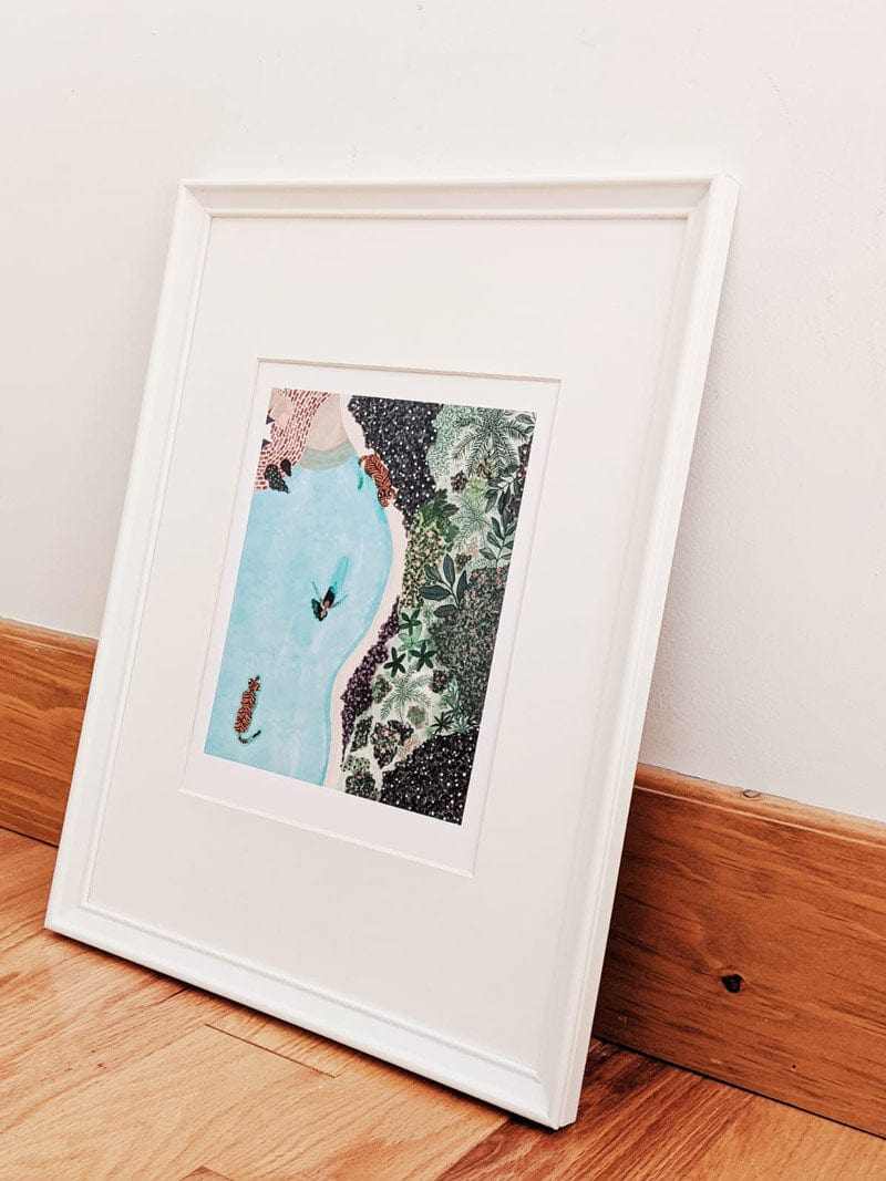 Framed artwork on a wooden floor with a white wall background