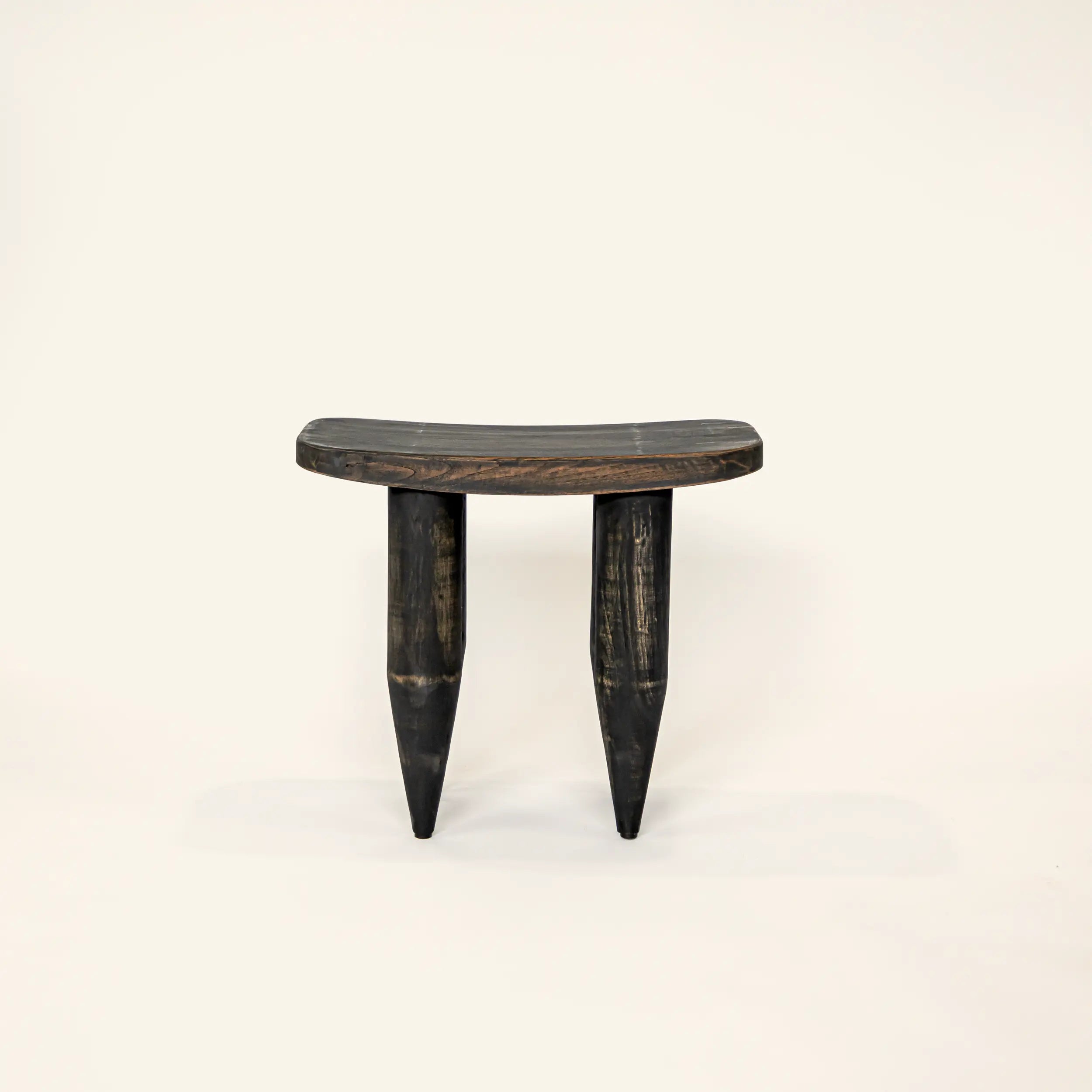 Wooden stool with a curved top and three thin legs on a white background