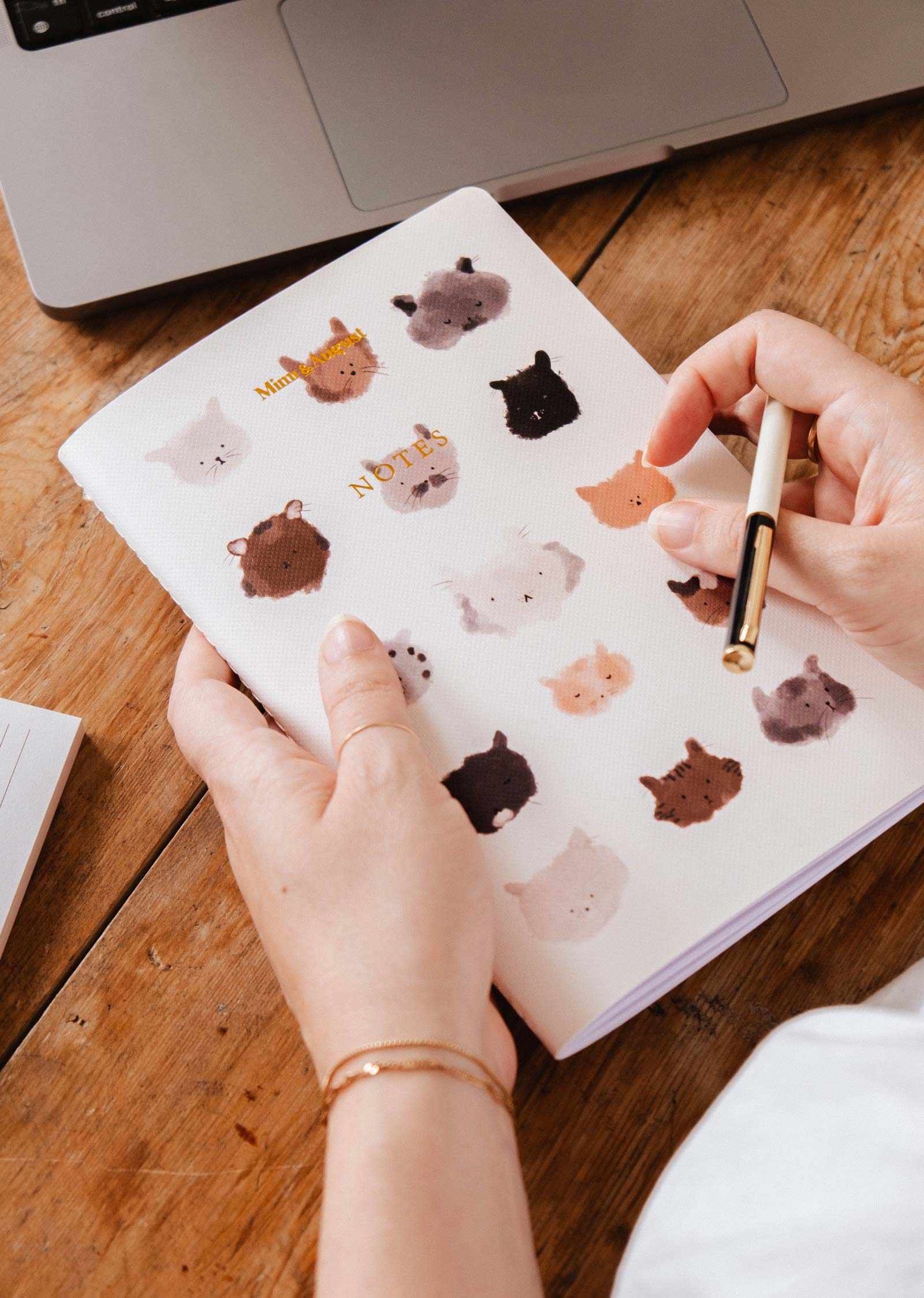 Person holding a notebook with animal stickers on a wooden table mimi-and-august