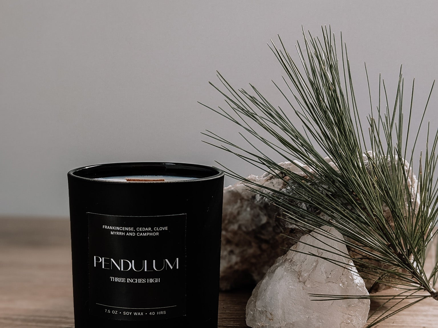 Black candle labeled 'Pendulum' on a wooden surface with a natural background