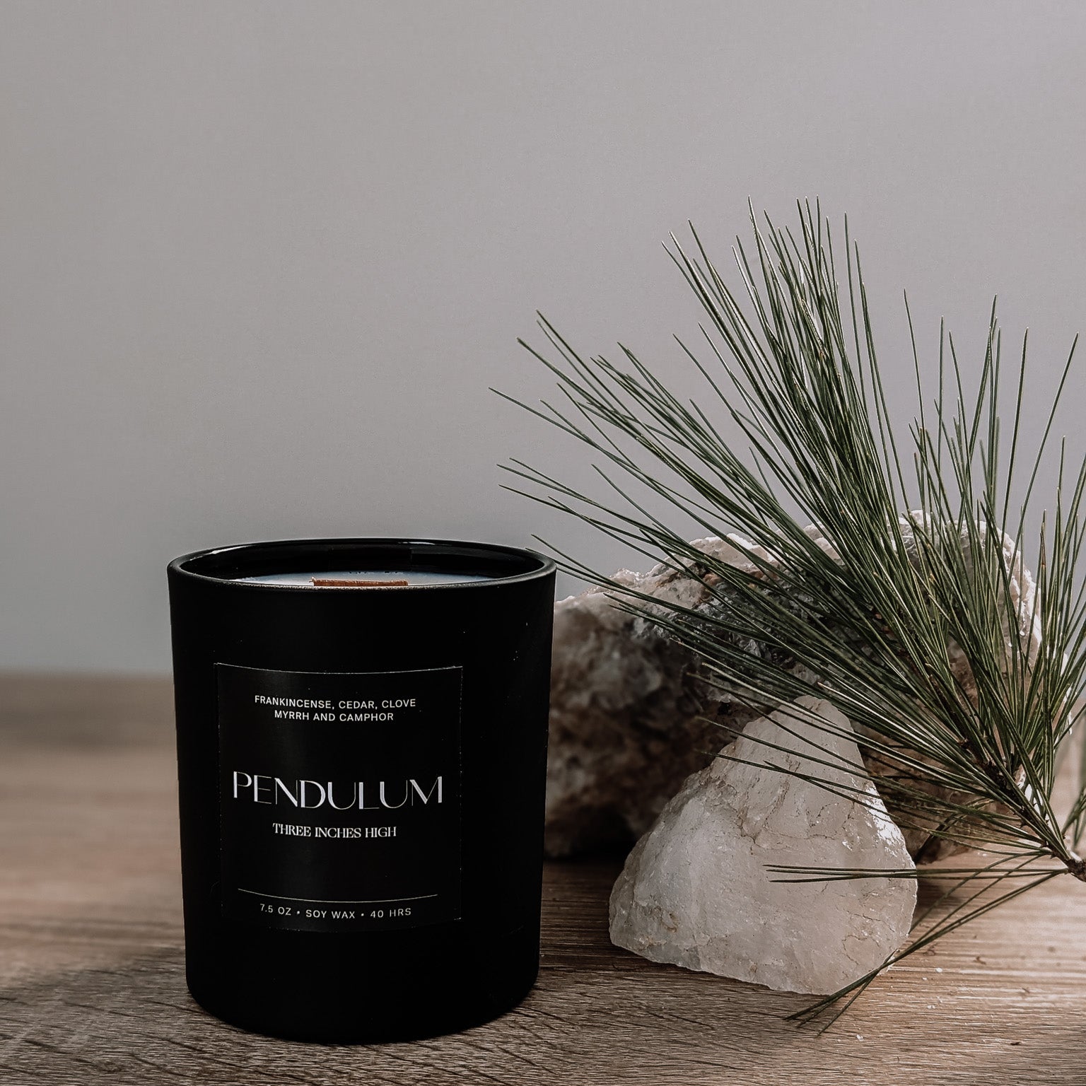 Black candle labeled 'Pendulum' on a wooden surface with a natural background