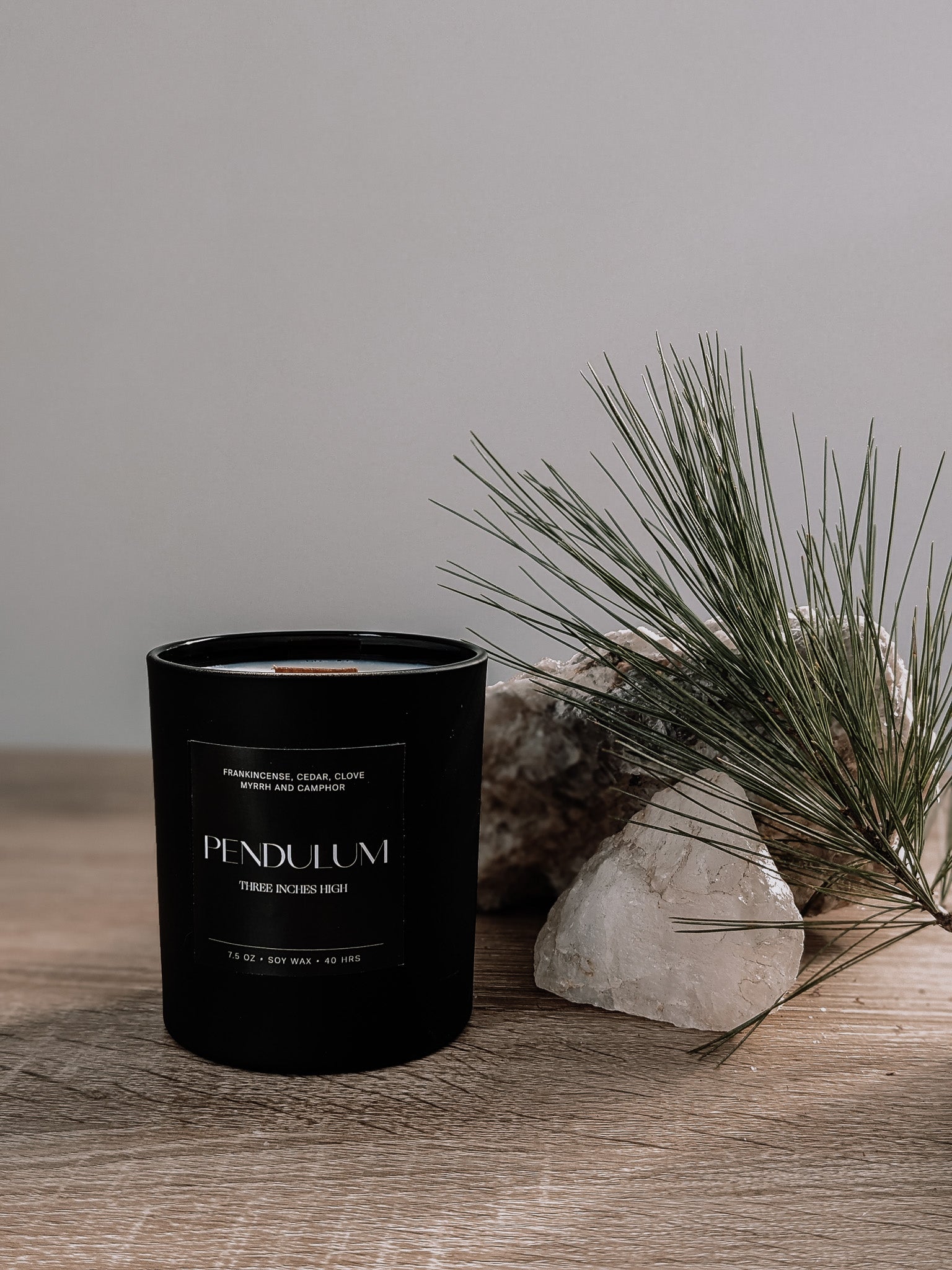 Black candle labeled 'Pendulum' on a wooden surface with a natural background