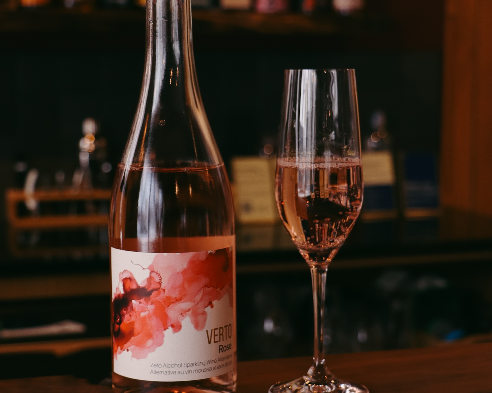 Bottle and glass of pink wine with a blurred bar background  The Sobr Market