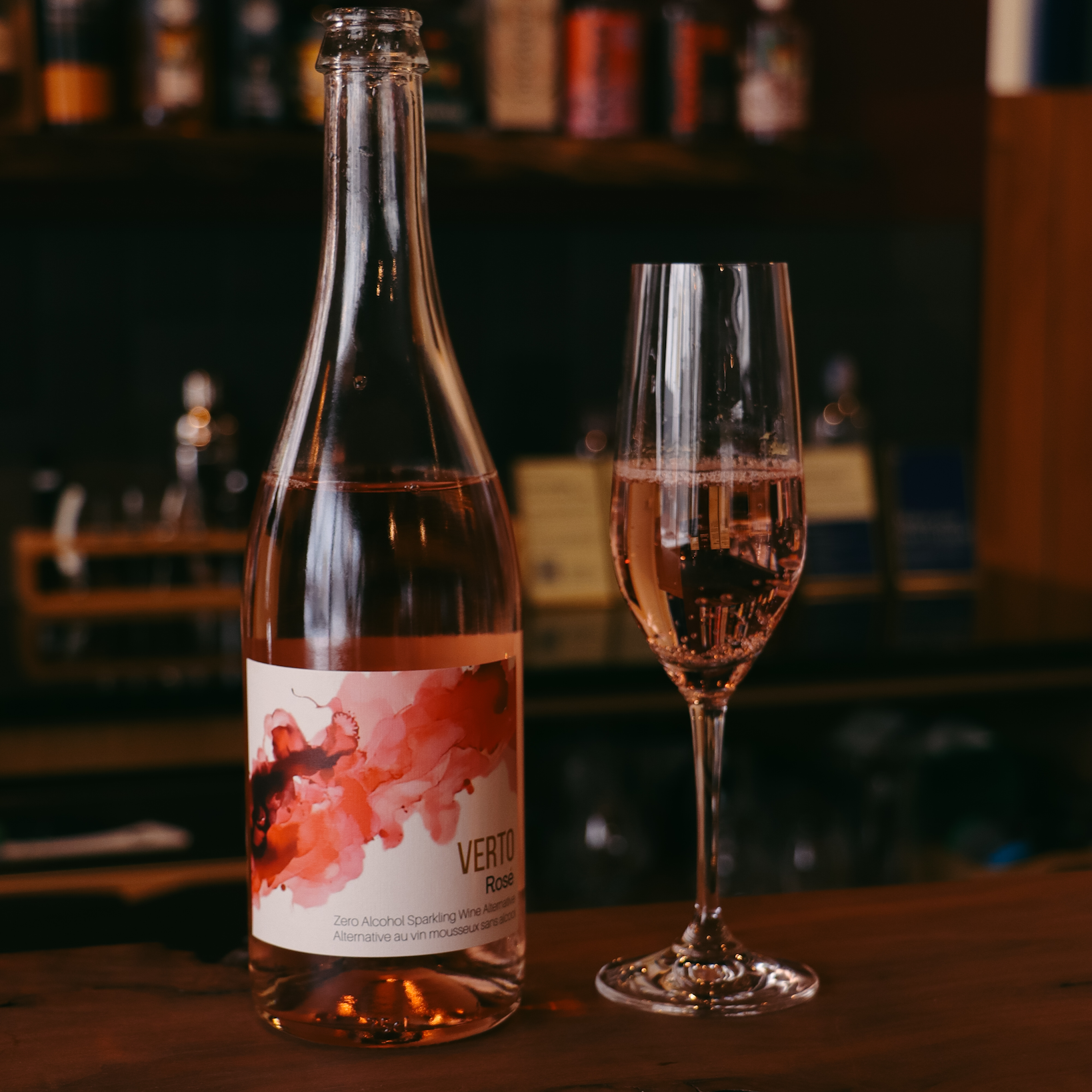 Bottle and glass of pink wine with a blurred bar background  The Sobr Market