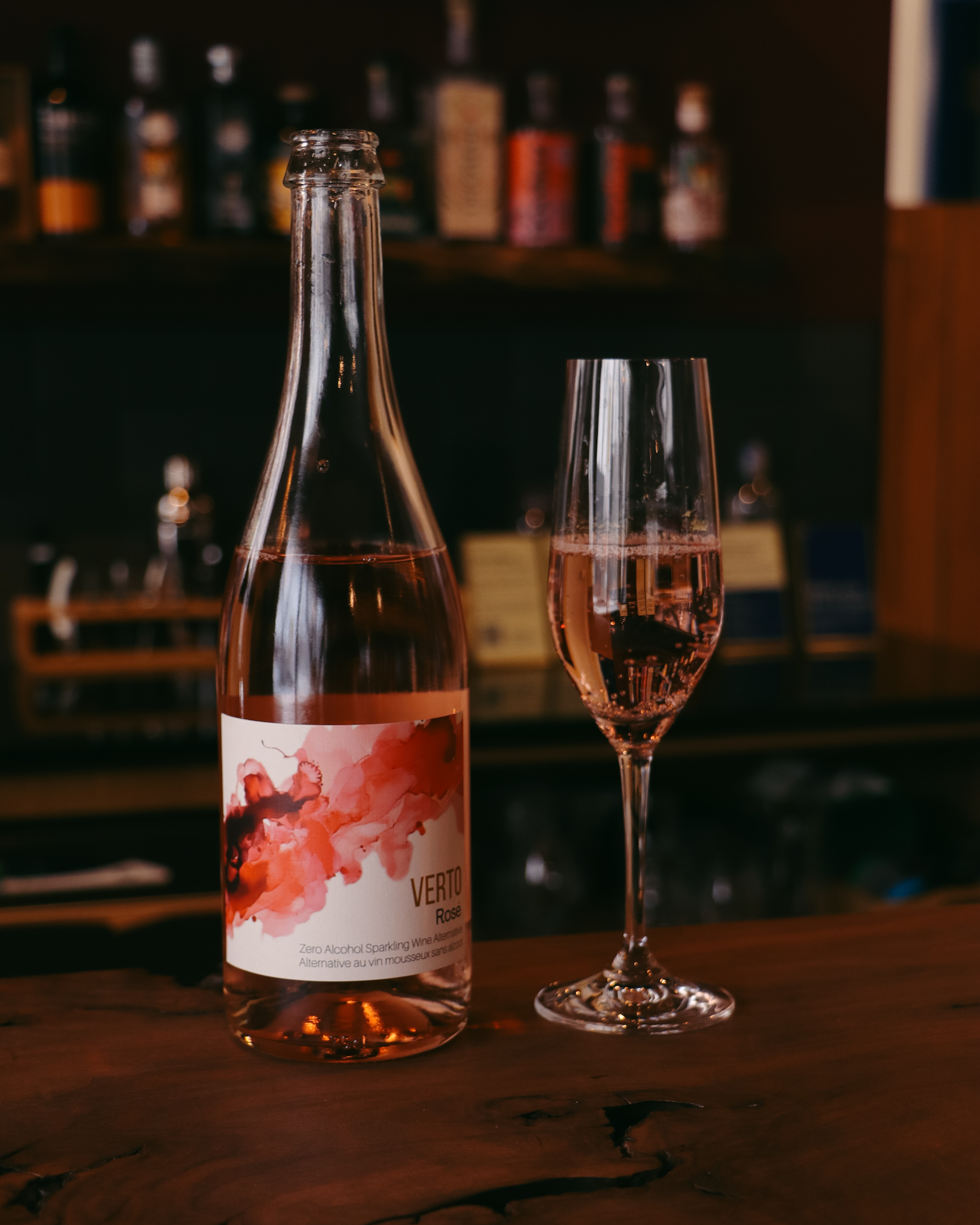 Bottle and glass of pink wine with a blurred bar background  The Sobr Market