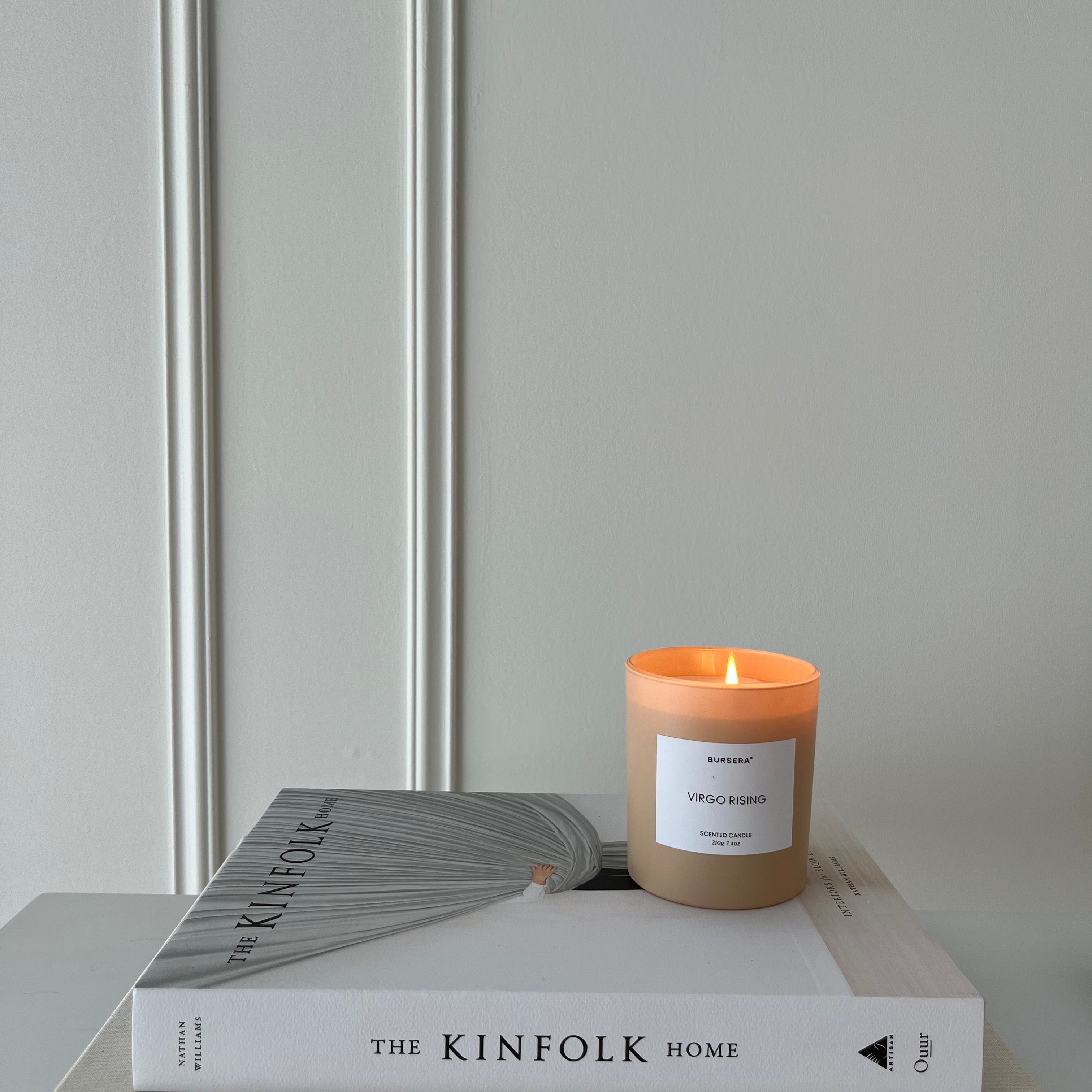 Candle burning on a stack of books with a neutral background