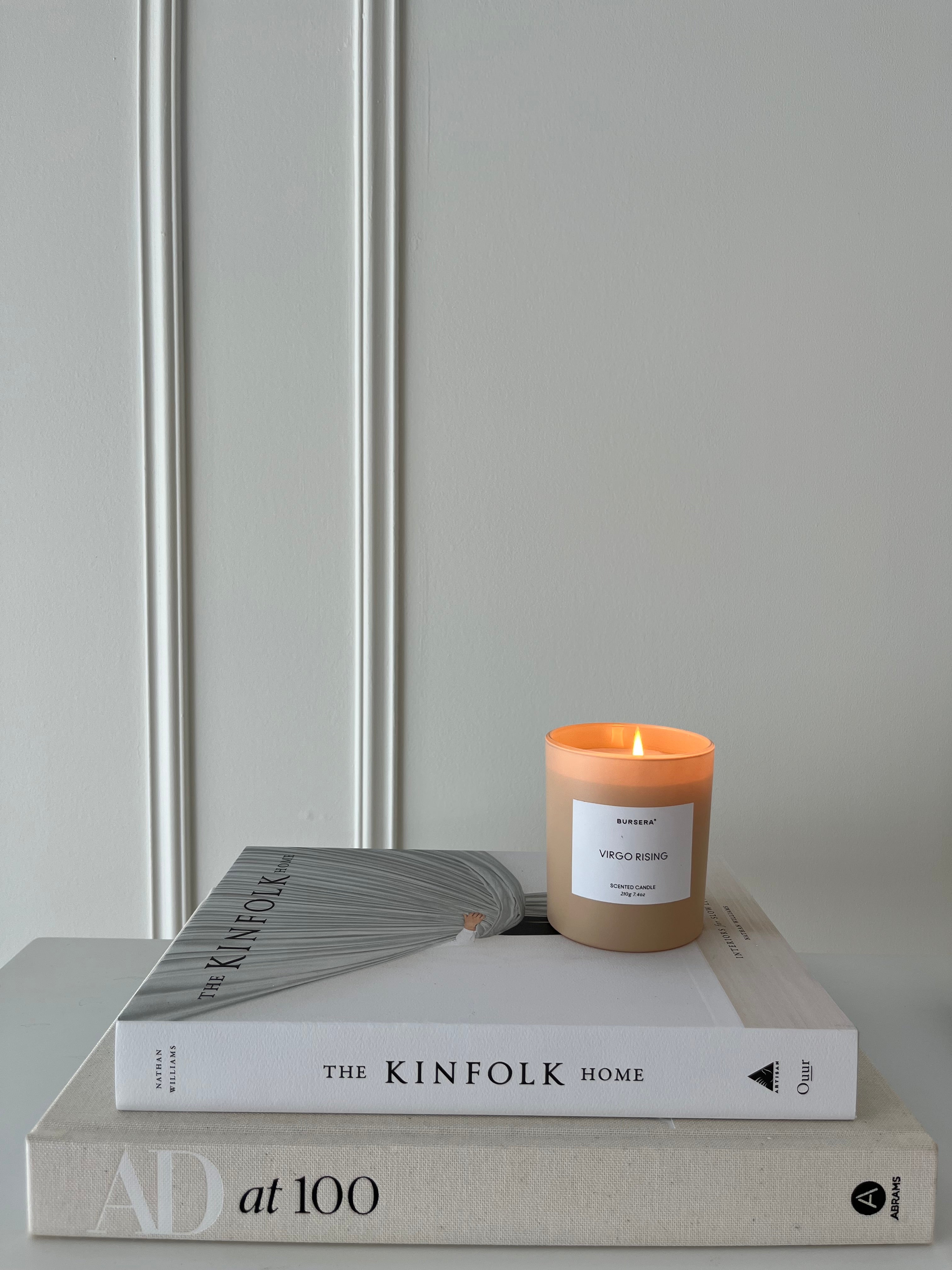 Candle burning on a stack of books with a neutral background