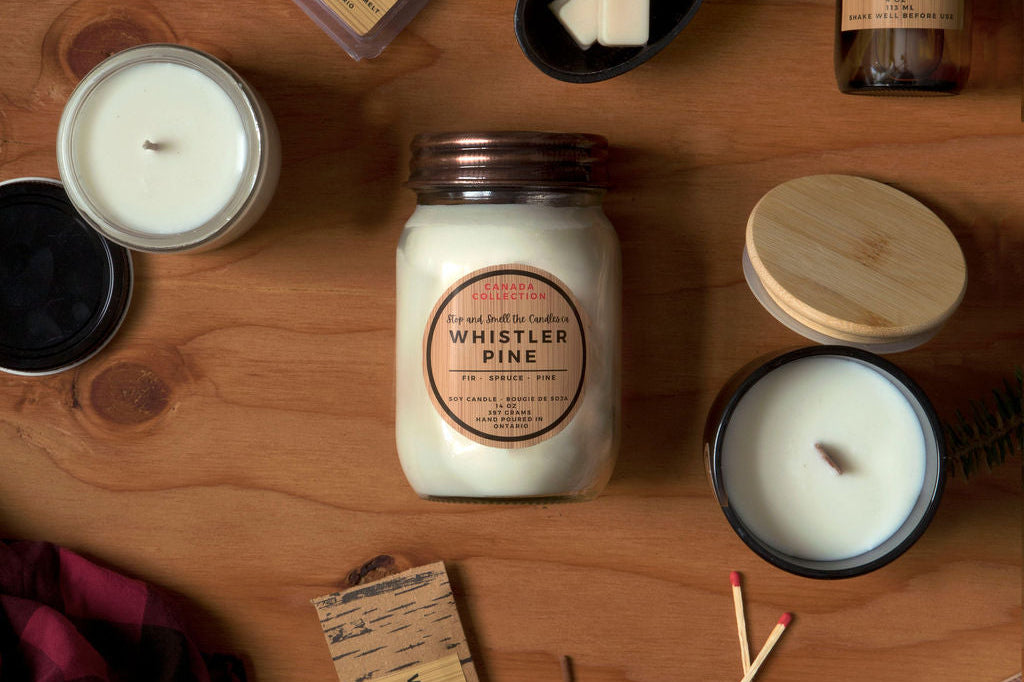 Collection of candles, matches, and decorative items on a wooden surface with 'Whistler Pine' branding.
