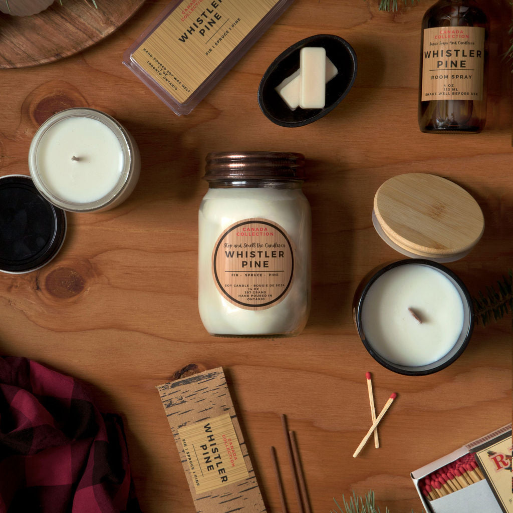 Collection of candles, matches, and decorative items on a wooden surface with 'Whistler Pine' branding.