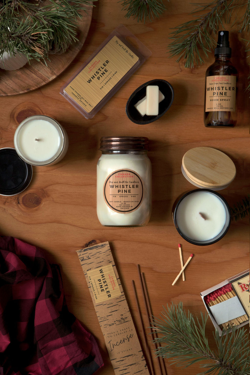 Collection of candles, matches, and decorative items on a wooden surface with 'Whistler Pine' branding.