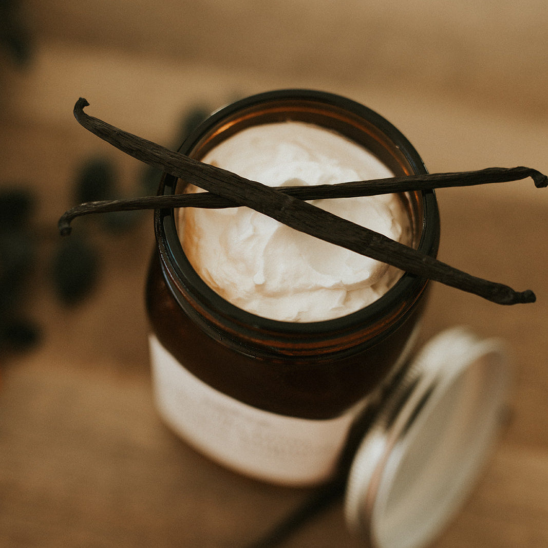Jar of whipped cream with vanilla beans on a wooden surface
