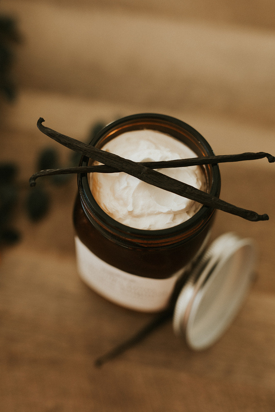 Jar of whipped cream with vanilla beans on a wooden surface