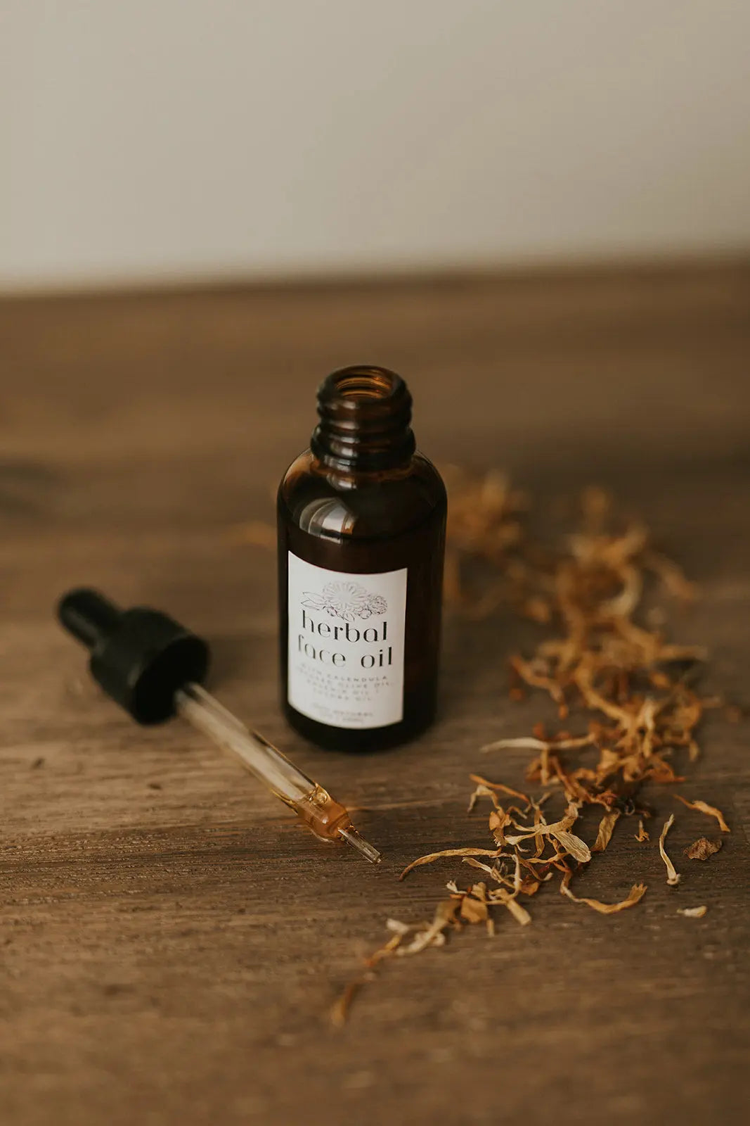 Bottle of herbal face oil with dropper on a wooden surface